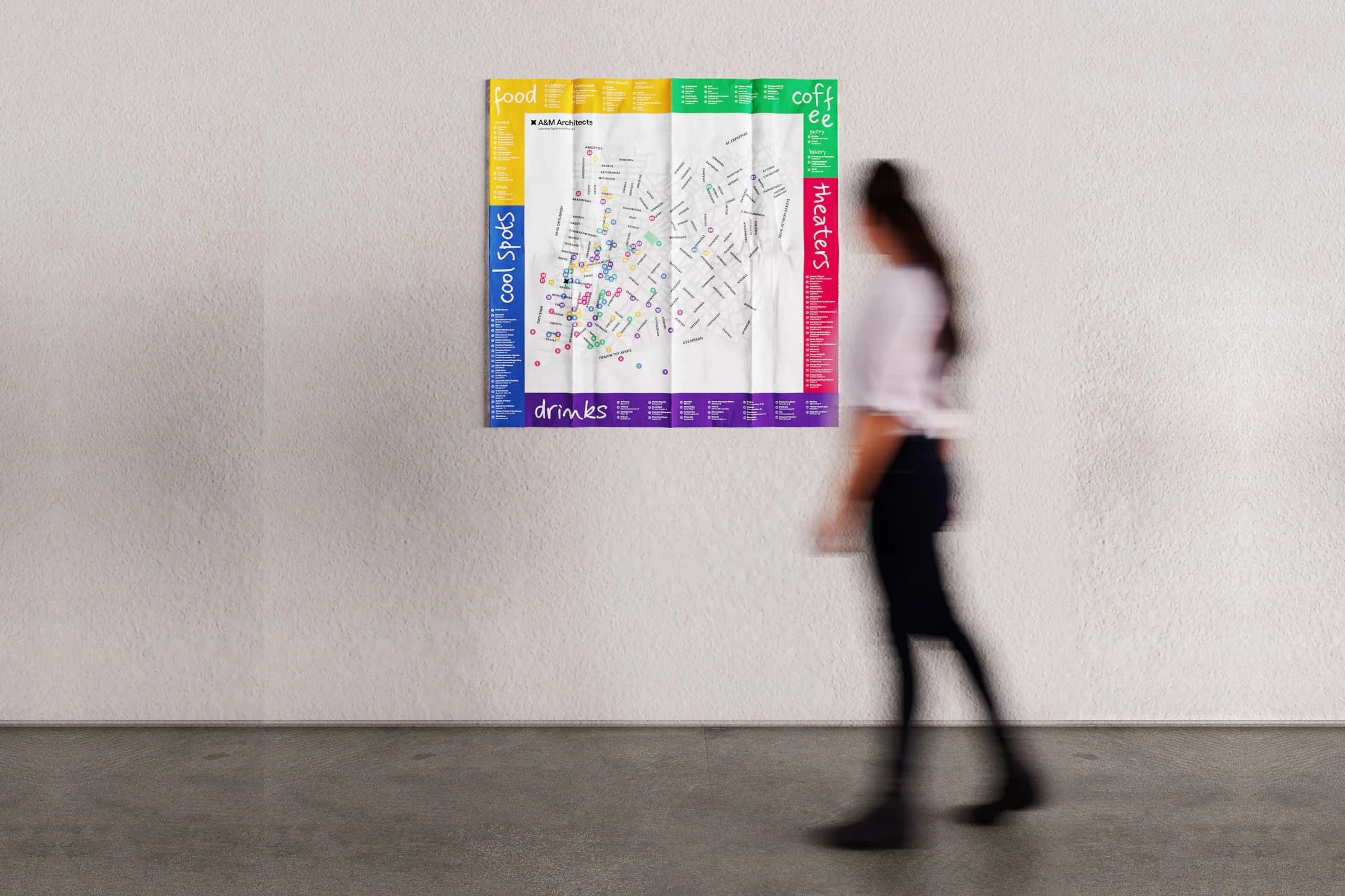 A woman walking past the Our Kypseli map hanging unfolded on a white wall