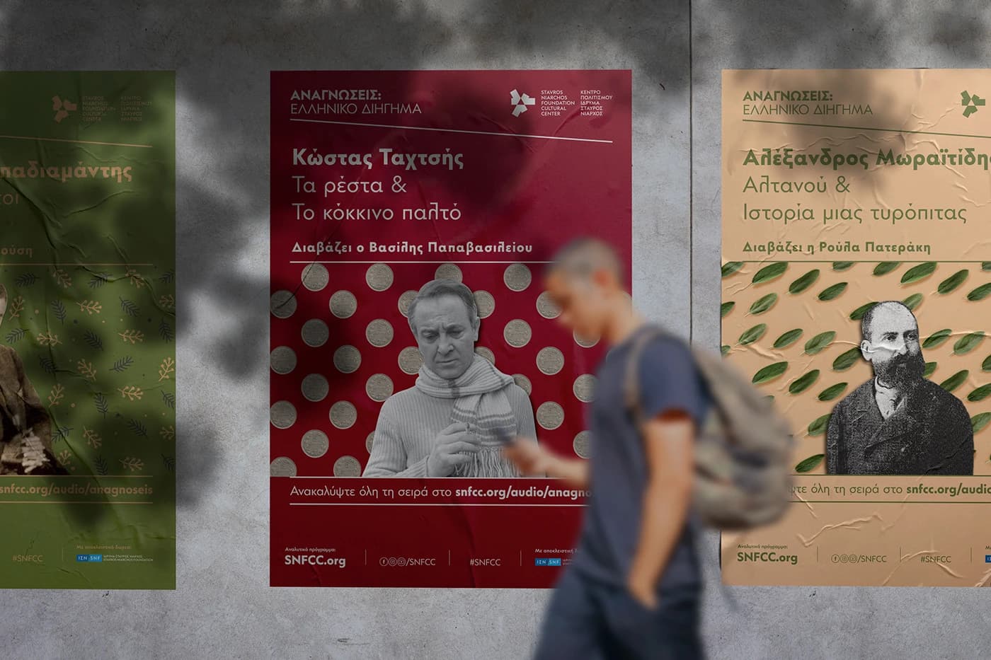 Posters for the SNFCC Readings on a wall, Kostas Tachtsis in red and Alexandros Moraitidis in beige, with a man walking past